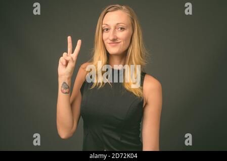 Jeune femme d'affaires avec cheveux blond droits sur fond gris Banque D'Images