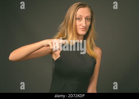 Jeune femme d'affaires avec cheveux blond droits sur fond gris Banque D'Images