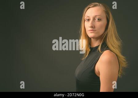 Jeune femme d'affaires avec cheveux blond droits sur fond gris Banque D'Images