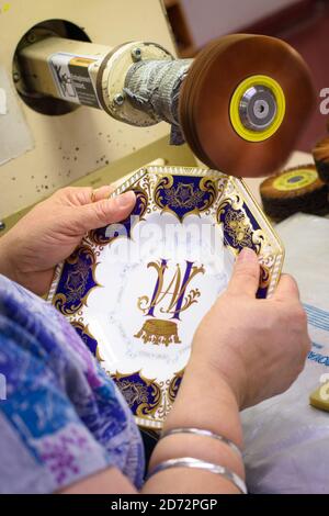 Un burnisher polit l'or 22ct sur une plaque octogonale qui commet le prochain mariage royal, à l'atelier du Royal Crown Derby à Derby, en Angleterre. La compagnie, qui remonte à 1750, vient d'annoncer ses pièces commémoratives en l'honneur du mariage royal entre le prince Harry et Meghan Markle. La Chine osseuse du Royal Crown Derby est encore entièrement fabriquée au Royaume-Uni, en utilisant des techniques largement inchangées depuis le XVIIIe siècle. Date de la photo: Jeudi 19 avril 2018. Le crédit photo devrait se lire: Matt Crossick/ EMPICS Entertainment. Banque D'Images