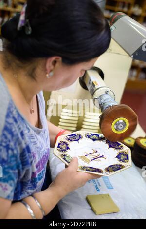 Un burnisher polit l'or 22ct sur une plaque octogonale qui commet le prochain mariage royal, à l'atelier du Royal Crown Derby à Derby, en Angleterre. La compagnie, qui remonte à 1750, vient d'annoncer ses pièces commémoratives en l'honneur du mariage royal entre le prince Harry et Meghan Markle. La Chine osseuse du Royal Crown Derby est encore entièrement fabriquée au Royaume-Uni, en utilisant des techniques largement inchangées depuis le XVIIIe siècle. Date de la photo: Jeudi 19 avril 2018. Le crédit photo devrait se lire: Matt Crossick/ EMPICS Entertainment. Banque D'Images