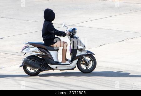 SAMUT PRAKAN, THAÏLANDE, JUL 23 2020, UNE jeune femme cachée dans un capot, fait une moto. Banque D'Images