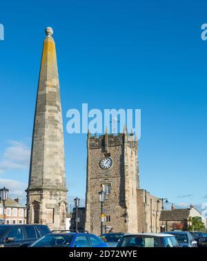 L'obélisque en pierre (Market Cross) et l'église de la Sainte-Trinité sur la place du marché à Richmond, dans le Yorkshire du Nord Banque D'Images