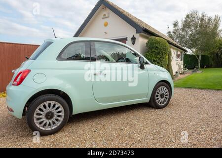 Vue au rez-de-chaussée d'une voiture italienne populaire vue sur une grande allée privée. Un garage et une partie d'un grand jardin sont vus au loin. Banque D'Images