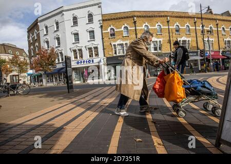 Homme sans-abri traversant la chaussée dans le centre-ville de Wimbledon, sud-ouest de Londres, Angleterre, Royaume-Uni Banque D'Images