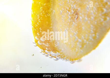 Détail de citron trempé dans de l'eau pleine de bulles se ferment haut Banque D'Images