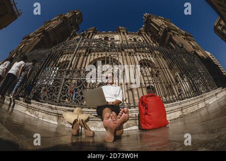 La femme est assise devant le bâtiment historique et travailler sur un ordinateur portable Banque D'Images