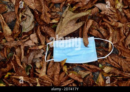 les masques écartés sur le sol parmi les feuilles brunes d'automne À londres, au Royaume-Uni, pandémie de Covid 19 2020 Banque D'Images