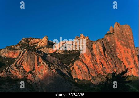 Les majestueux Mallos de Riglos, une passerelle naturelle spectaculaire vers les Pyrénées, brillent orange-rouge dans la lumière du soleil du soir dans la province de Huesca, Aragon, Espagne. Los Mallos (les maillets) s'est formé il y a au moins 20 millions d'années, lorsque les matériaux délavés des pentes pyrénéennes se sont compactés avec du calcaire pour former des roches conglomérées. Les «maillets» distinctifs, sculptés par l'érosion, sont une frontière physique entre les contreforts pyrénéens et le bassin de l'Ebre, qui s'élève à environ 300 m (980 pi). Au XIe siècle, la région de Mallos fut brièvement un royaume indépendant après que Pedro, roi d'Aragon, l'eut donné comme une dot. Banque D'Images