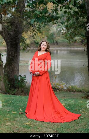 Femme vêtue d'une robe rouge pour les photos de maternité Banque D'Images