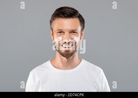 Homme d'âge moyen avec de la crème sur les joues contre les rides Banque D'Images