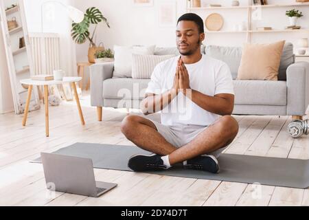 African American Man Doing Yoga assis sur un ordinateur portable à la maison Banque D'Images