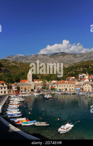 L'eau bleu-vert claire bordée de petits bateaux amarrés remplit le petit port de la côte Adriatique pittoresque de Jablanac, dans le comté de Lika-Senj, dans l'ouest de la Croatie. Le village, mentionné pour la première fois au XIIe siècle, se trouve sous la majeure partie de la chaîne de montagnes Velebit de 1,757 m (5,764 pi). Jusqu'en 1212, un ferry pour voitures et passagers reliait Jablanac à l'île offshore de Rab. Banque D'Images