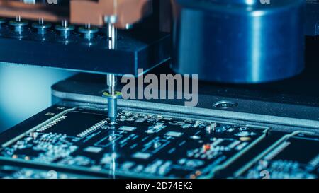 Gros plan Macro de la carte de circuit imprimé électronique en cours d'assemblage avec bras robotisé automatisé, technologie de montage en surface connectant les micropuces Banque D'Images