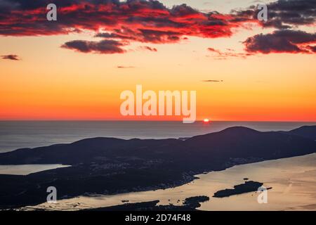 Vue sur KotorBay au coucher du soleil depuis la route de montagne en serpentin au-dessus du ciel avec des nuages au coucher du soleil. Banque D'Images