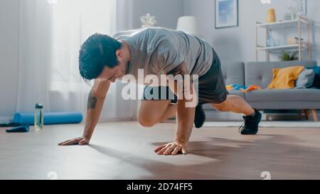 Smiling strong Athletic Fit Man en T-shirt et short est Faire des exercices Mountain Climber à la maison dans son spacieux et Salon lumineux avec Banque D'Images