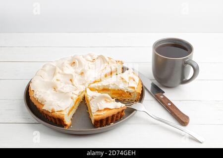 Tarte à l'abricot maison décorée de meringue et d'une tasse de thé sur une table en bois blanc. CopySpace. Banque D'Images