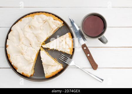 Tarte à l'abricot maison décorée de meringue et d'une tasse de thé sur une table en bois blanc. Vue de dessus. Banque D'Images