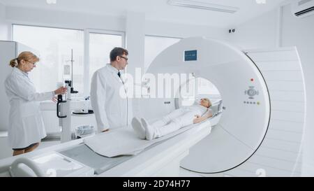 En laboratoire médical, les femmes radiologues et les hommes médecins contrôlent et contrôlent l'IRM ou l'acquisition CT avec une patiente en cours de procédure. Haute technologie moderne Banque D'Images