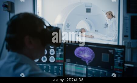 Concept futuriste : dans la salle de contrôle médicale, le médecin porte un casque de réalité virtuelle moniteurs patient soumis à une procédure d'examen IRM ou TDM. Ordinateur Banque D'Images