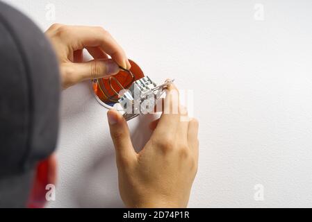 électricien installant un interrupteur d'éclairage sur un mur peint à l'aide d'un tournevis. Homme installant l'interrupteur d'éclairage après rénovation. Banque D'Images