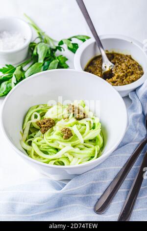 Des nuddles de Zucchini sains avec du pesto sur fond blanc Banque D'Images