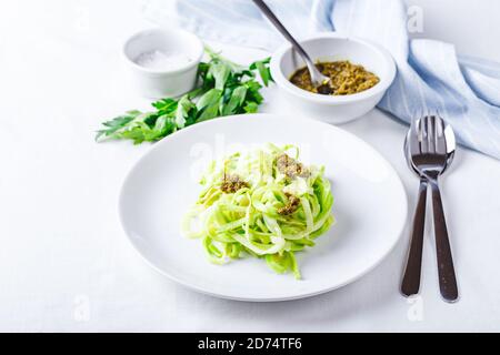 Des nuddles de Zucchini sains avec du pesto sur fond blanc Banque D'Images