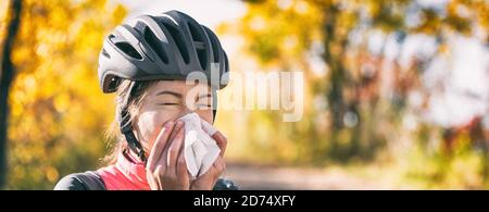 Toux dans les tissus recouvrant le nez et la bouche lorsqu'on tousse à l'extérieur comme directives d'hygiène COVID-19 pour la prévention de la propagation du coronavirus. Cycliste fille Banque D'Images