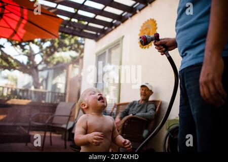 Oncle pulvérisation neveu avec le tuyau comme Grandpa Smiles à San Diego Banque D'Images