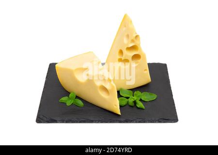 Deux quartiers de fromage frais et de feuilles de basilic sur un panneau en pierre noire isolé sur fond blanc Banque D'Images