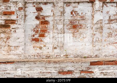 Mur de bâtiment abandonné avec des briques rouges recouvertes de stuc Banque D'Images