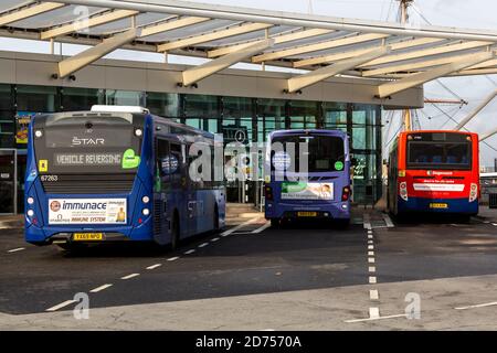 Un bus à impériale unique entrant dans un terminal de bus à côté de deux bus stationnés dans des baies Banque D'Images