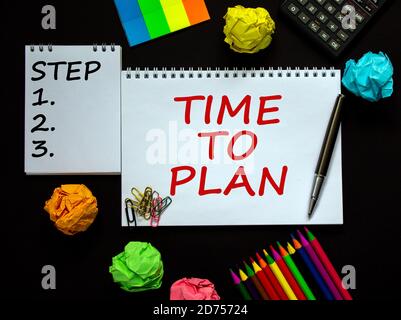 Notes blanches avec inscription « Time to plan » et « Step 1, 2, 3 » sur une belle table noire, papier de couleur, crayons de couleur, trombones, stylo et calcul Banque D'Images