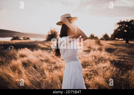 Brunette fille dans une robe blanche avec des cheveux bouclés sur un chapeau de boatman Banque D'Images