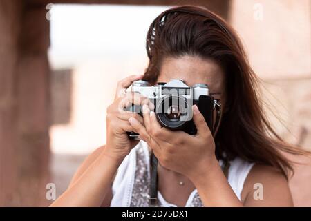 Jeune femme prenant une photo vers l'appareil photo avec un ancien appareil photo. Concept de photographie Banque D'Images