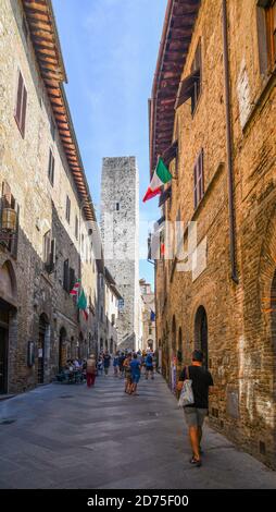 Centre historique de San Gimignano, site de l'UNESCO, avec des touristes marchant dans une ruelle étroite et la Torre dei Cugnanesi médiévale, Sienne, Toscane, Italie Banque D'Images