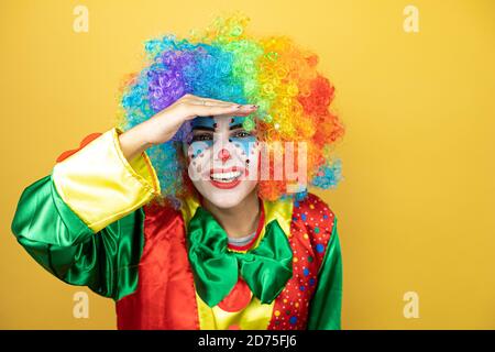 Clown se tenant sur fond jaune insolé jaune à la recherche de quelque chose Banque D'Images