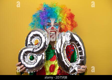 Clown se tenant sur fond jaune insolé jaune et portant un numéro 80. Concept de célébration. Banque D'Images