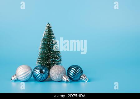 Photo du petit sapin jouet et de quatre belles boules isolé sur fond bleu clair avec espace de copie Banque D'Images