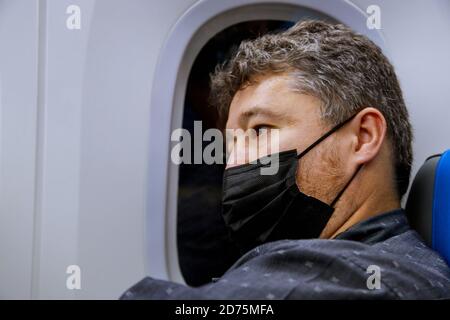 Nouveau voyage normal pendant une pandémie, un homme portant un masque facial assis dans un passager voyageant en avion dans la cabine de l'avion Voyage aérien Covid 19 Banque D'Images