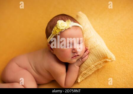 portrait d'une belle petite fille de sept jours. Elle dort dans une position de ftal courbé sur une couverture jaune Banque D'Images