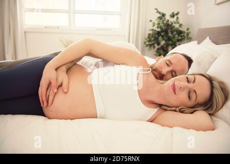 Belle femme enceinte et son beau mari passant du temps ensemble au lit Banque D'Images
