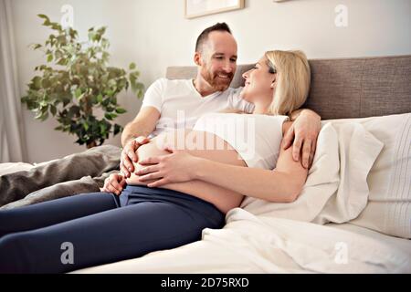 Belle femme enceinte et son beau mari passant du temps ensemble au lit Banque D'Images