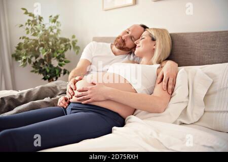 Belle femme enceinte et son beau mari passant du temps ensemble au lit Banque D'Images