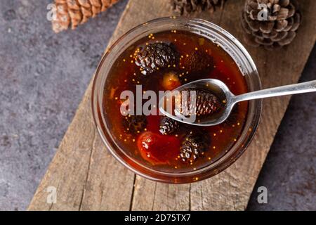 Les jeunes cônes de pin se coince dans un bol en verre sur une planche en bois. Confiture délicieuse avec les petits cônes de pin. Banque D'Images