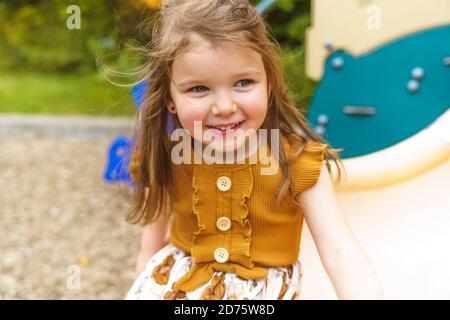 Happy Smiling Child Girl jouant au terrain de jeu à l'extérieur dans un Parc agréable sur un toboggan Banque D'Images
