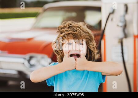 Un enfant avec une voiture rétro à la station-service vintage, ça va. Banque D'Images