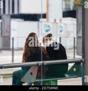 Strasbourg, France - 18 octobre 2020 : vue latérale - vue arrière de deux jeunes filles avec masque chirurgical de protection en attente de tramway à la station regardant sur l'écran du smartphone Banque D'Images