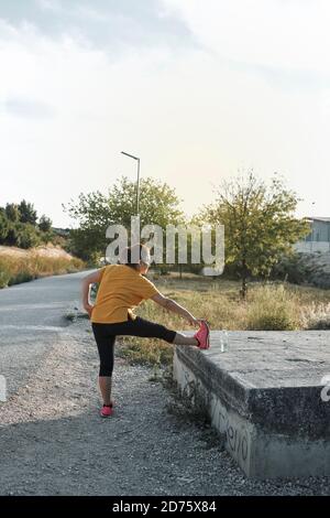 Une femme d'âge moyen fait des jambes s'étirant à l'extérieur Banque D'Images