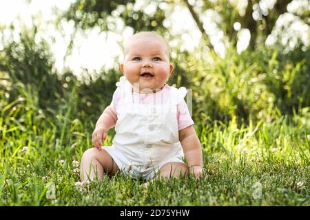 Bonne adorable fillette chubby assise sur l'herbe Banque D'Images